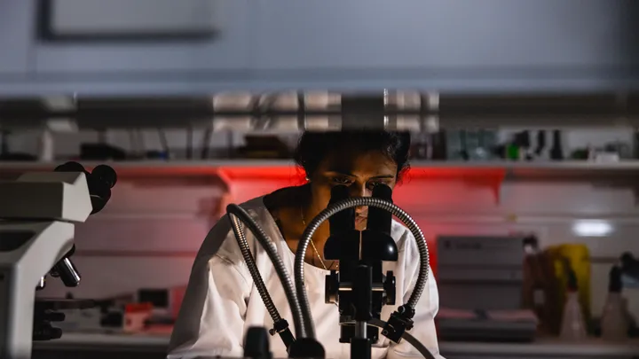 A female scientist looks down a microscope