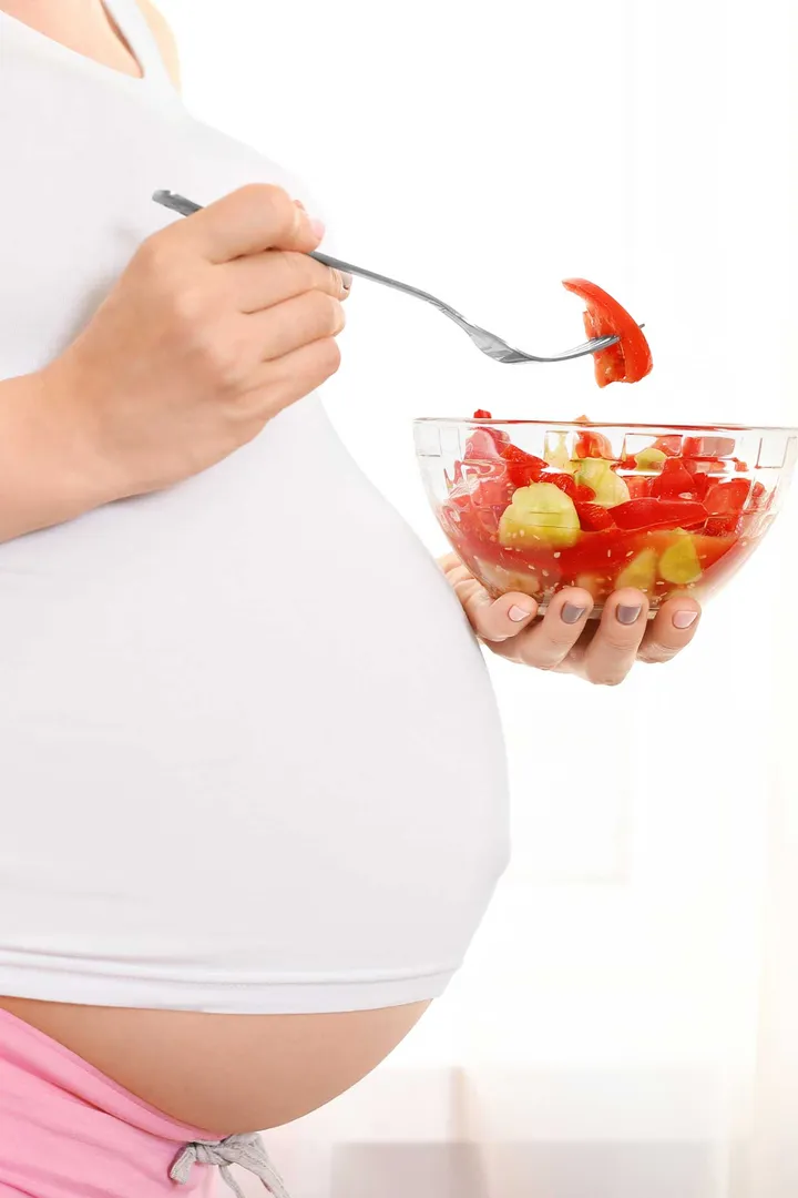 A pregnant women with a bowl of healthy food